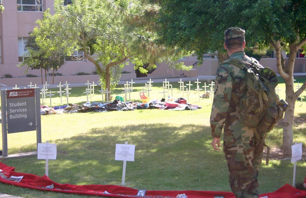 A ROTC soldier pauses at the memorial of crosses for those who have died in Iraq.