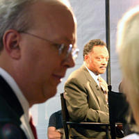 Karl Rove standing in the shadows while Rev. Jackson is interviewed on Fox News, reflective of their preferred roles in American